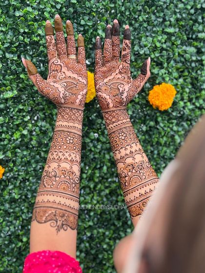 A clear shot of the same bridal mehendi against a green wall, making the intricate patterns stand out.