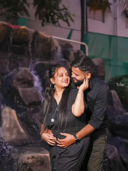An intimate embrace in front of a waterfall feature. The natural elements and the couple's connection are the focus of this romantic shot.