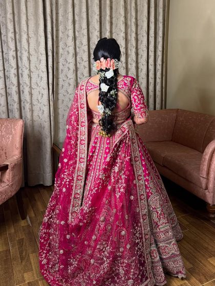 The back view of the bridal look, showing the detailed embroidery of the lehenga and the beautiful floral braid.