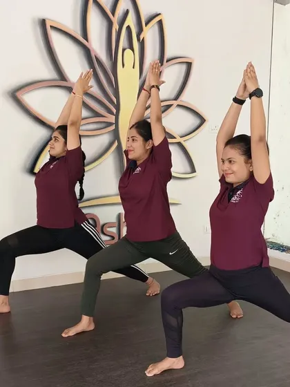 Three students hold Virabhadrasana I (Warrior I) in unison, demonstrating strength and alignment.