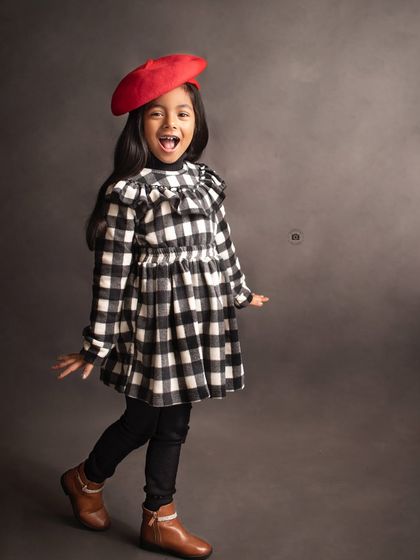 A playful and chic portrait inspired by Parisian style. The red beret and gingham dress create a fun, fashionable look.