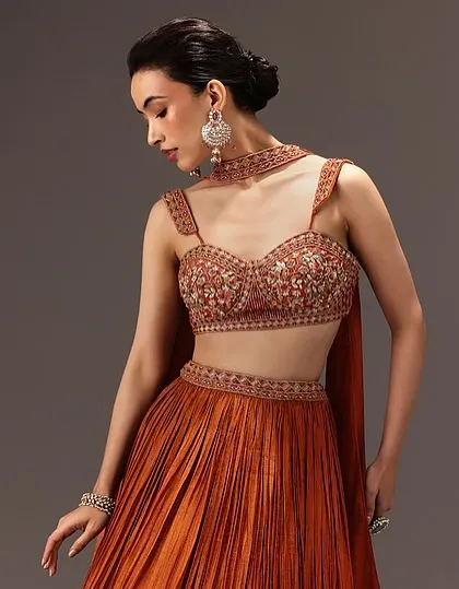 Another example of a versatile soft glam look for Kalki Fashion. The low bun and neutral makeup palette complement this rust-colored lehenga, making it suitable for various festive occasions.