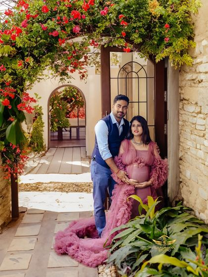 A beautiful couple's portrait set in a rustic, European-inspired doorway covered in flowers. The dusty rose gown complements the romantic setting perfectly.
