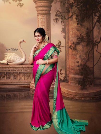 A solo portrait of the mother-to-be in a vibrant pink and green saree. Her gentle expression and the serene, artistic background create a picture of pure grace.