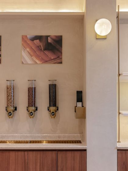 The interactive 'Nostimo' counter at Entisi allows customers to engage directly with the product. We designed this feature with wall-mounted dispensers and a minimal brass and wood counter to create a hands-on, memorable brand experience.