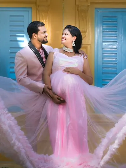 A maternity photo with a flowing pink gown against a colorful yellow and blue wall, creating a vibrant and joyful image.