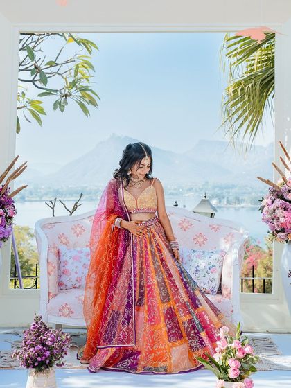 A full-length portrait of the bride in her vibrant lehenga, set against the stunning Udaipur backdrop.