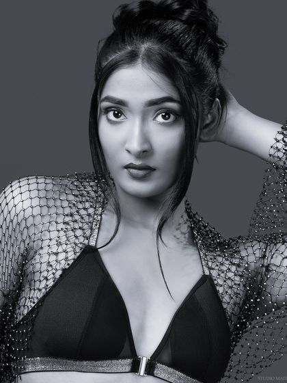 A direct and confident black and white portrait of the model in the bralette and mesh shrug, perfect for a portfolio headshot.