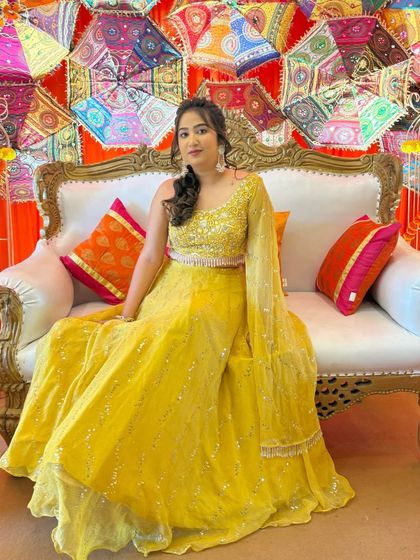 The bride on her decorated Haldi stage. The colorful background and her vibrant yellow lehenga are perfectly balanced by the soft, glowing makeup.