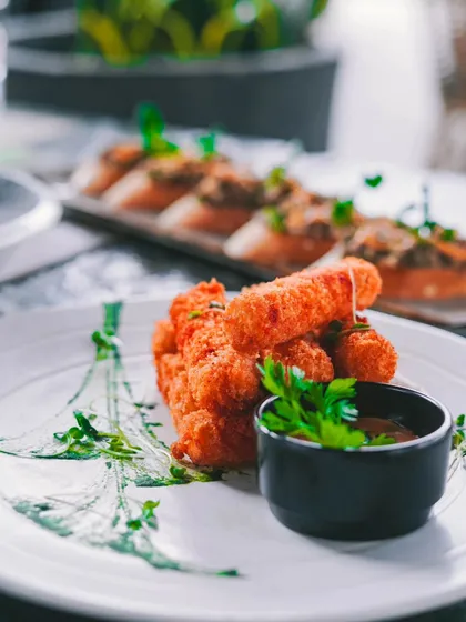 Our crispy fried appetizers, like these cheese sticks, are perfect for sharing. The artistic plating with fresh herbs makes them even more special.