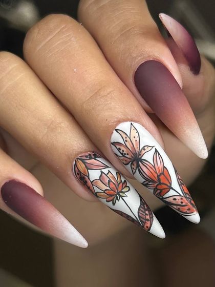 A beautiful autumn-themed nail art set on extra-long stiletto nails. The design features a matte ombré effect with hand-painted fall leaves on the accent nails.