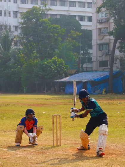 A young batsman focused on the ball, ready to play his shot in a T20 practice game.