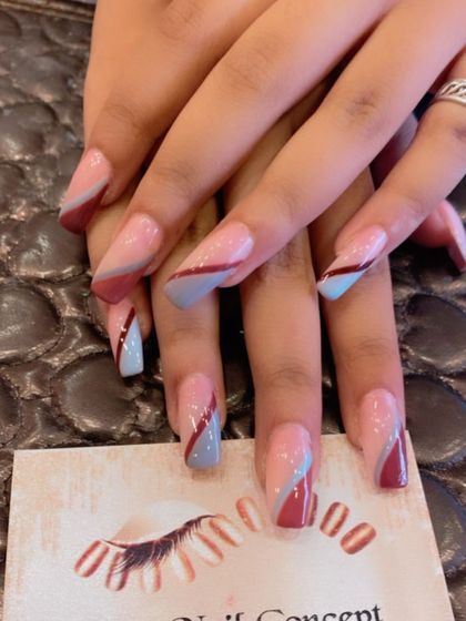 A modern and artistic design on long, square nails. The sheer pink base is decorated with abstract, overlapping swirls of muted blue and maroon.