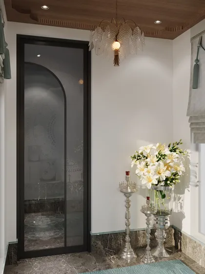The entrance to the mandir is marked by a simple glass door, allowing it to feel connected to the rest of the home while maintaining its sanctity. Elegant lighting and fresh flowers complete this tranquil space.