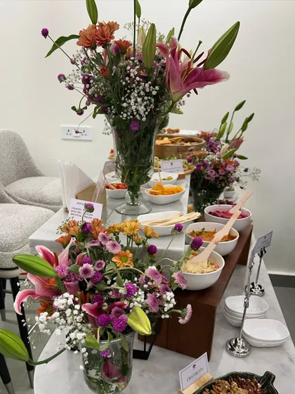 The full appetizer station at a store opening, beautifully decorated with fresh flowers. We believe the food setup should be a visual centerpiece of the event.