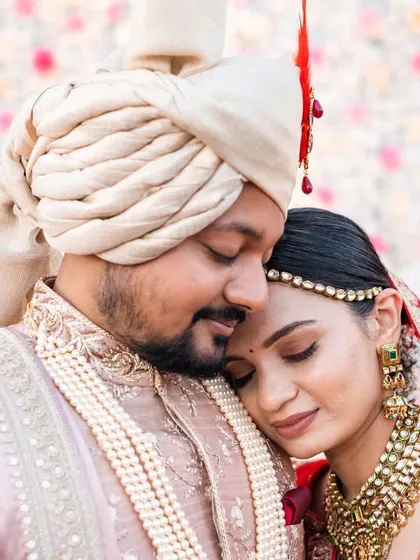 An intimate close-up from a Gujarati wedding. The bride resting on the groom's shoulder shows a moment of quiet connection amidst the day's events.