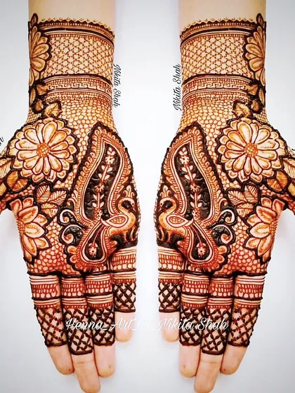 An Indian designer mehendi with a mix of floral and peacock motifs. The combination of bold figures and delicate net patterns creates a balanced and beautiful look.