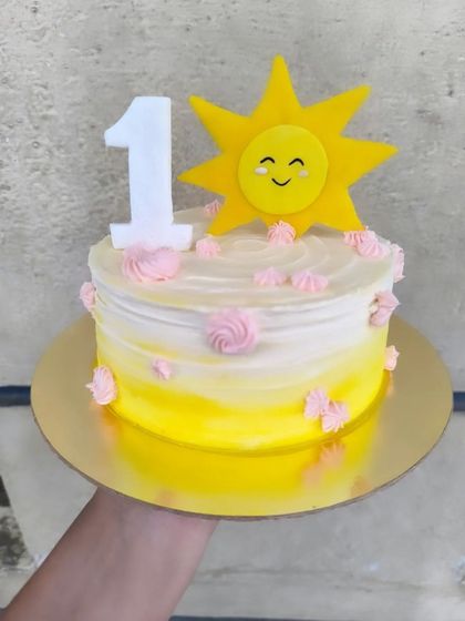 A sunshine smash cake for a first birthday. This cheerful yellow ombre cake is topped with a smiling sun and the number one, perfect for a fun and messy photoshoot.
