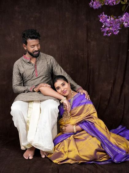 A serene couple portrait with the mother-to-be resting her head on her partner's shoulder. The rich silk saree and traditional attire create a look of timeless elegance and deep connection.