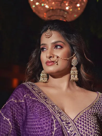A close-up of this purple-toned reception look. The nath adds a traditional touch to the modern, glamorous makeup.