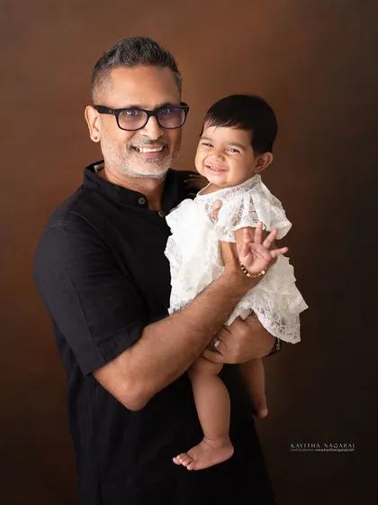 The joy of being a parent is in the little moments. A father holds his eight-month-old daughter, her happy wave and his proud smile creating a perfect family memory.