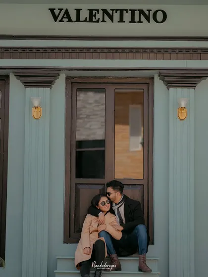 A tender moment with the groom kissing his bride's forehead as they sit on the steps of a chic storefront.