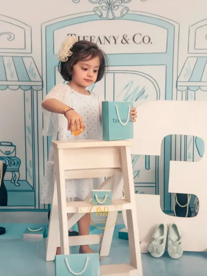 A candid moment from the "Tiffany & Co." shoot, as the birthday girl plays with props and a shopping bag.
