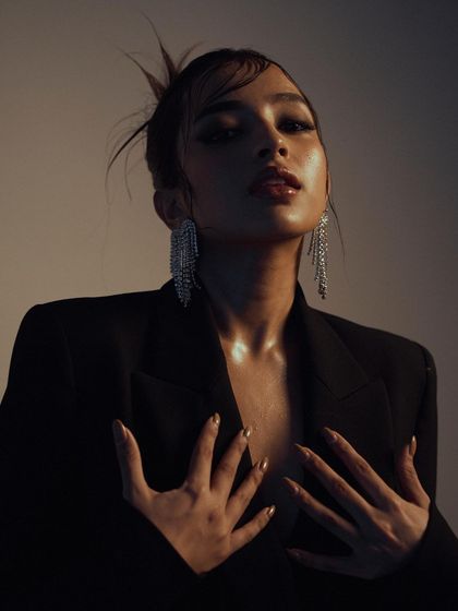 An intimate and expressive close-up. The warm, soft lighting and the model's pose create a sensual and glamorous mood, perfect for a beauty or jewelry campaign.