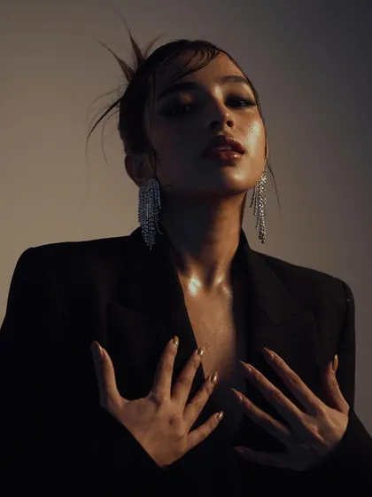 An intimate and expressive close-up. The warm, soft lighting and the model's pose create a sensual and glamorous mood, perfect for a beauty or jewelry campaign.