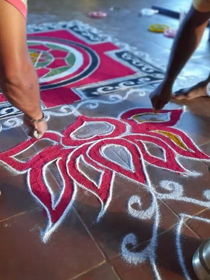 Hands carefully creating the lotus pattern in the center of the rangoli. The lotus symbolizes purity and spiritual unfoldment.