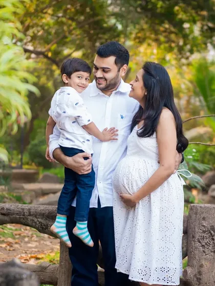 A beautiful family portrait. The parents-to-be and their son share a loving look, excited for the new baby to join their family.