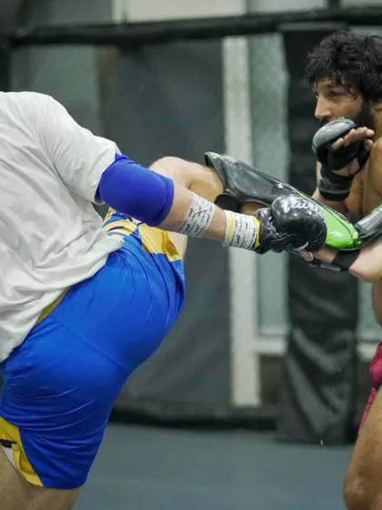 A fighter checks a powerful kick during a hard spar. This level of reaction and toughness is built through countless hours of dedicated training.