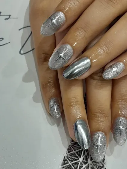 This design mixes textures for a unique look. We combined silver glitter nails with full-coverage silver chrome accent nails, all tied together with a starburst detail.