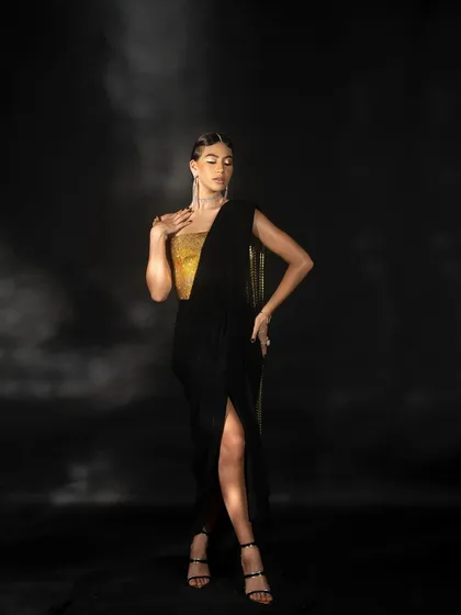 A full-length studio shot capturing the elegance of the black and gold Nikhil Thampi dress. The soft lighting and classic pose create a timeless and sophisticated fashion image.