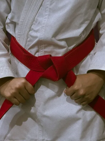 The red belt, a symbol of advanced skill and responsibility, tied with precision. It represents a significant milestone in a karateka's journey.
