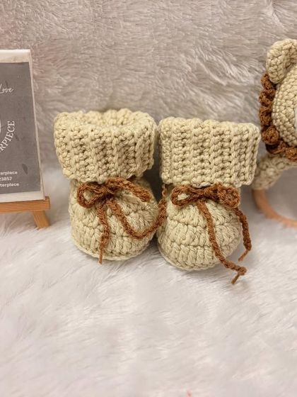 This unisex baby set includes cozy crochet booties and a matching lion rattle with a wooden teether ring. It's a perfect gift for a baby shower, designed to be both snuggly and playful.