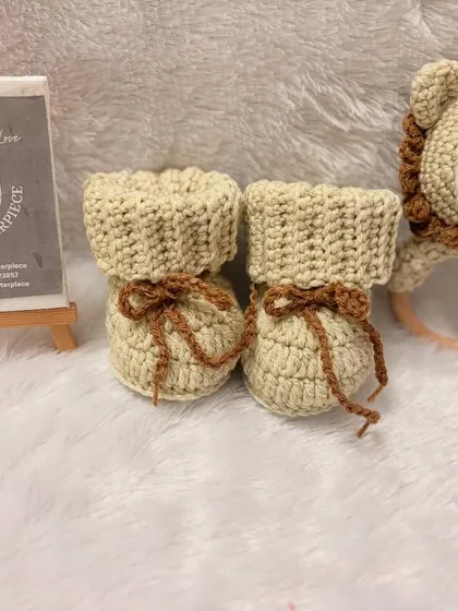 This unisex gift set features cozy, fold-over booties and a matching lion rattle with a wooden teether ring, perfect for snuggles and playtime.