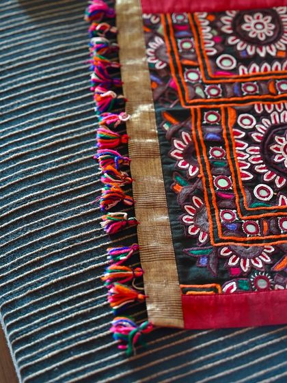 A close-up of a custom runner, showing the intricate Kutch embroidery and the colorful handmade tassels that provide a finishing touch.