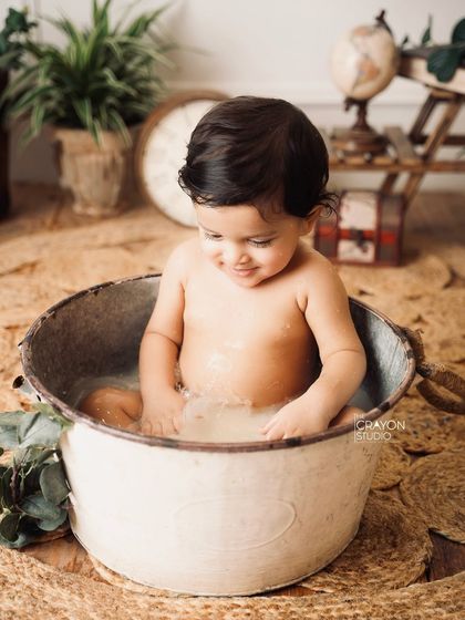 A fun splash session to celebrate a milestone. This little boy enjoys playing in a rustic tub of water, a perfect way to capture pure, simple joy.