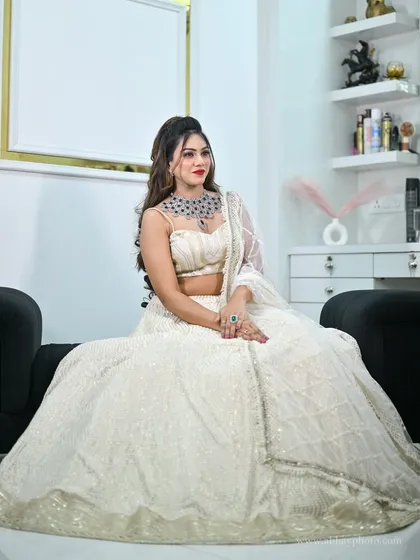 A model seated gracefully in the ivory chikankari lehenga, showcasing the full skirt and the modern diamond jewellery.