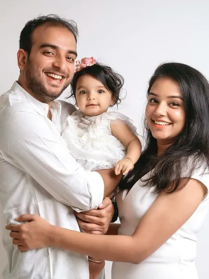 A beautiful family of three, all dressed in white for a timeless and classic studio portrait.