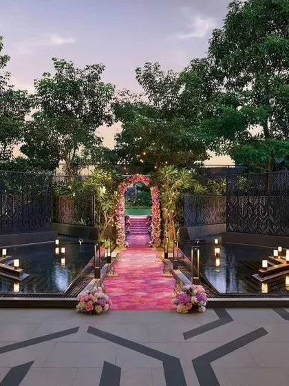 This dreamy pastel passage was designed for a lawn wedding. A floral arch marks the beginning of a pink carpeted walkway that crosses over a water body, with floating candles adding to the magical ambiance.