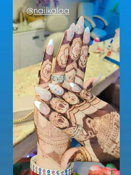 A stunning bridal look featuring French ombre nails with glitter and 3D crystal accents. The design perfectly complements the intricate bridal henna.