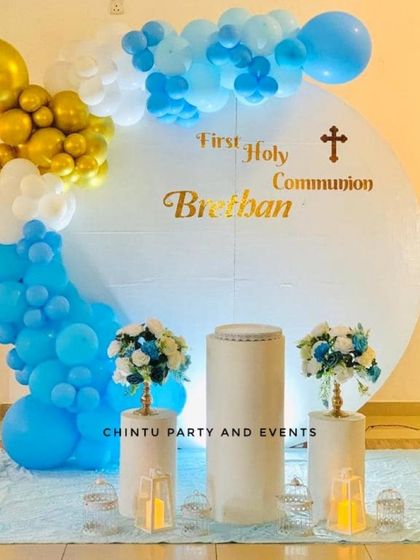 A First Holy Communion decoration for a boy in shades of blue, white, and gold. The circular backdrop is personalized with the name and a cross.