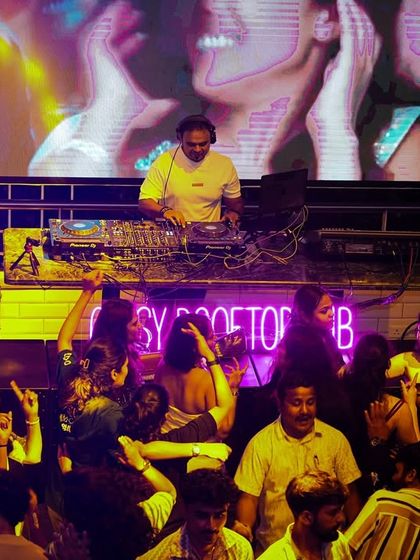 A view from the dance floor looking up at the DJ booth. The large screen and elevated stage create a focal point for the entire party.