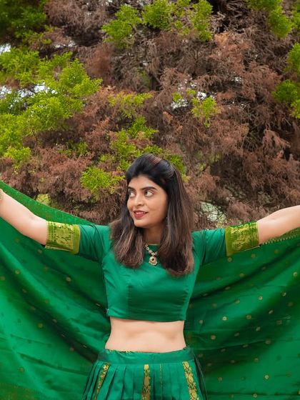 A vibrant outdoor portrait showcasing a beautiful green traditional outfit. The movement of the fabric adds a dynamic and joyful element to the photo.