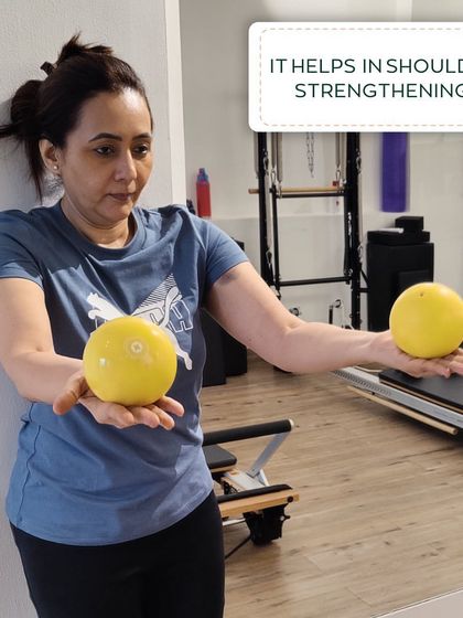 A client demonstrating a shoulder strengthening exercise with toning balls, showcasing one of the many props we use to keep workouts interesting.