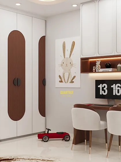 The study area in the kids' room, designed to accommodate two children. The space includes a long desk, overhead cabinets, and open shelving, ensuring everything is organized and within reach.