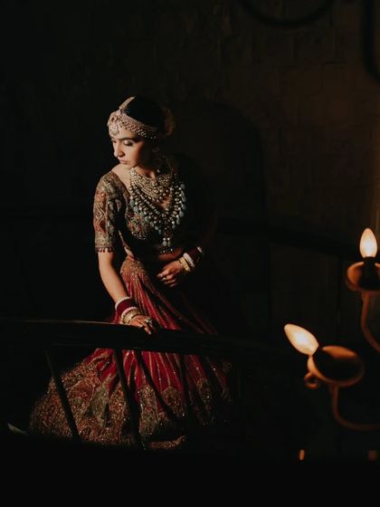 A moody and atmospheric bridal portrait, with the bride looking down from a staircase, illuminated by soft, warm light.