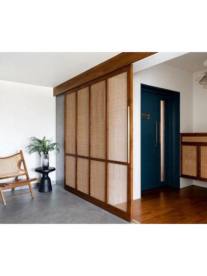 A large sliding panel of teak and rattan at the entrance foyer. This element can be moved to conceal or reveal the main door, adding a layer of privacy and a touch of handcrafted warmth right at the entry.